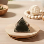 Load image into Gallery viewer, Pyramid-shaped crystal on a wooden stand with a blurred background