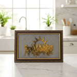 Load image into Gallery viewer, Decorative wall art with gold silhouette of people and sun in a brown frame on a kitchen counter.
