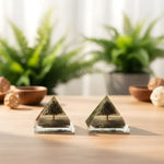 Load image into Gallery viewer, Two pyramid-shaped decorative items on a wooden surface with plants in the background