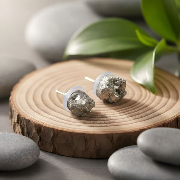 Silver earrings on a wooden surface with stones and leaves in the background